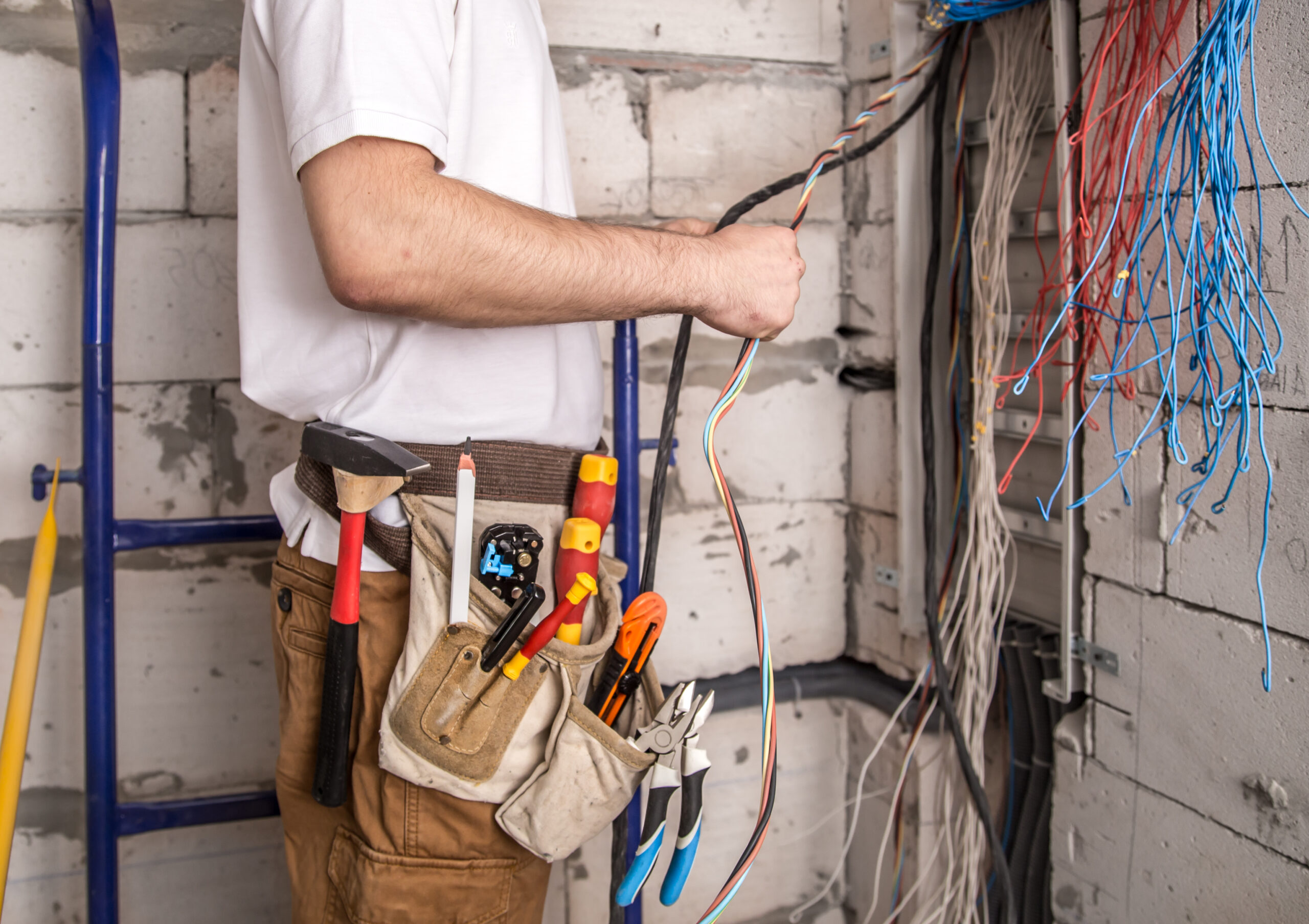 An electrician measuring cable length and grouping wires together
