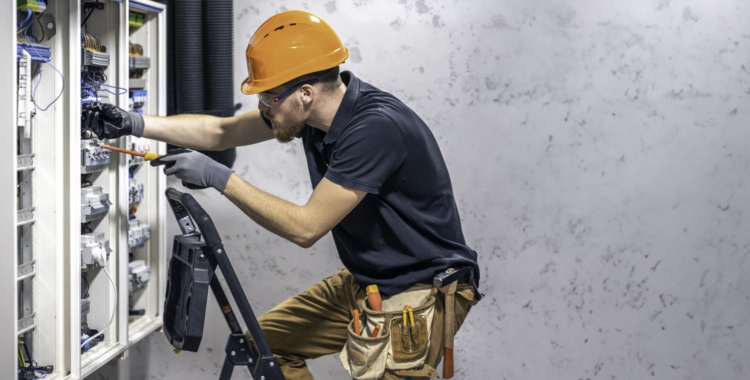 A male electrician working on a switchboard performing cable sizing - how to size cables