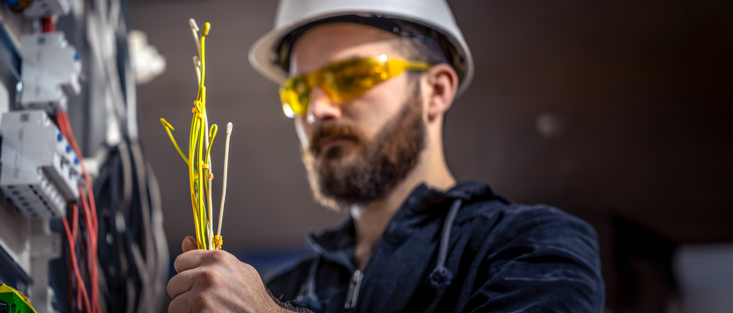 male electrician working switchboard to size cables